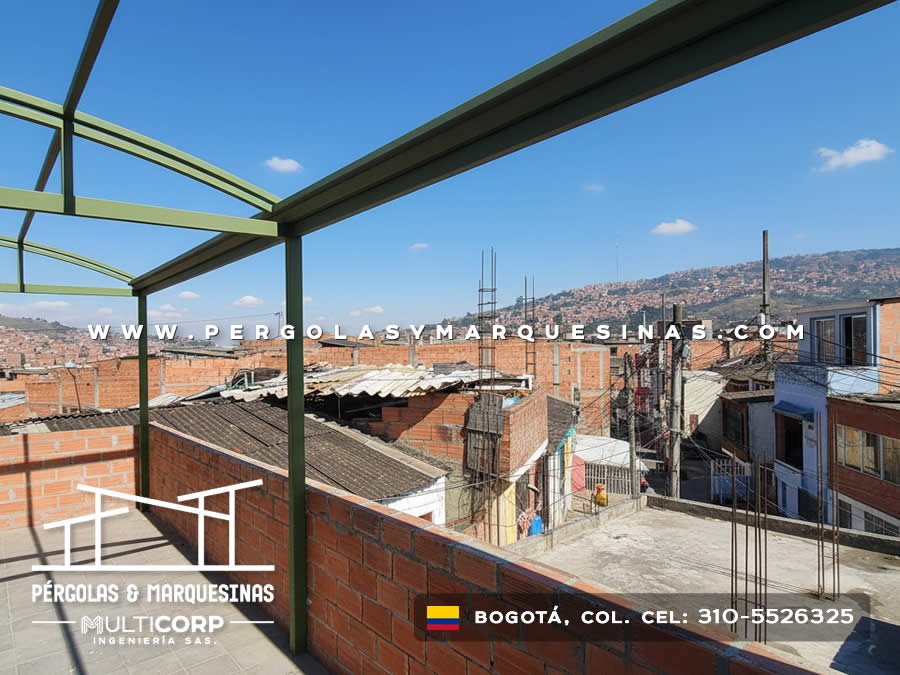 Pergola metalica verde estructura abierta sobre terraza azotea edificio ladrillo con barrio urbano y montanas en Bogotá, Colombia. Multicorp Ingeniería SAS. Pergola metalica verde estructura abierta sobre terraza azotea edificio ladrillo con barrio urbano y montanas en Bogotá, Colombia. Multicorp Ingeniería SAS.