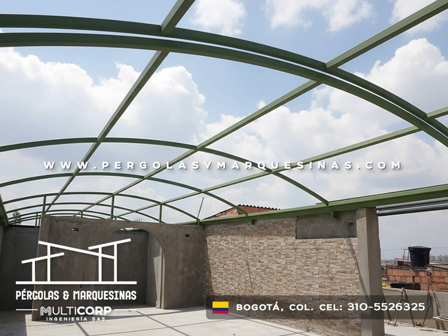 Estructura curva metalica verde sobre azotea edificio con muro piedra y edificios urbanos al fondo en Bogotá, Colombia. Multicorp Ingeniería SAS. Estructura curva metalica verde sobre azotea edificio con muro piedra y edificios urbanos al fondo en Bogotá, Colombia. Multicorp Ingeniería SAS.