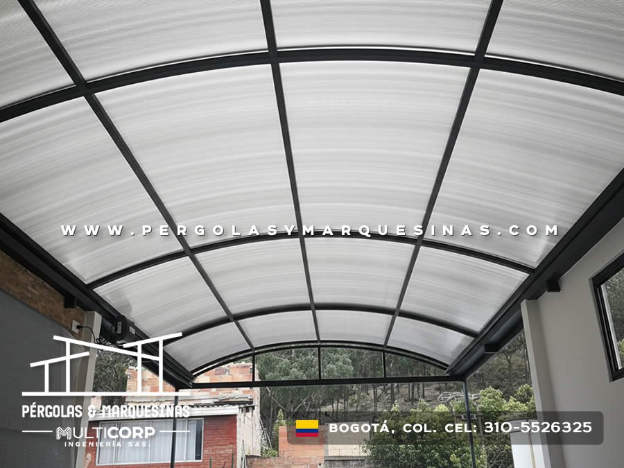 Cubierta curva metalica policarbonato interior arcos negros vista jardin vivienda ladrillo arboles en Bogotá, Colombia. Multicorp Ingeniería SAS. Cubierta curva metalica policarbonato interior arcos negros vista jardin vivienda ladrillo arboles en Bogotá, Colombia. Multicorp Ingeniería SAS.