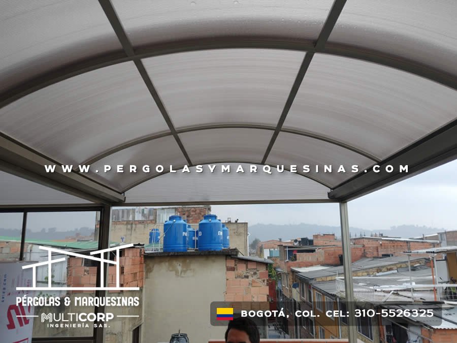 Cubierta arqueada de policarbonato translucido con perfiles metalicos sobre terraza con vista urbana en Bogotá, Colombia. Multicorp Ingeniería SAS.