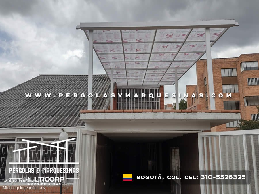 Pergola metalica blanca con paneles de policarbonato translucido sobre entrada vehicular de conjunto residencial en Bogotá, Colombia. Multicorp Ingeniería SAS.