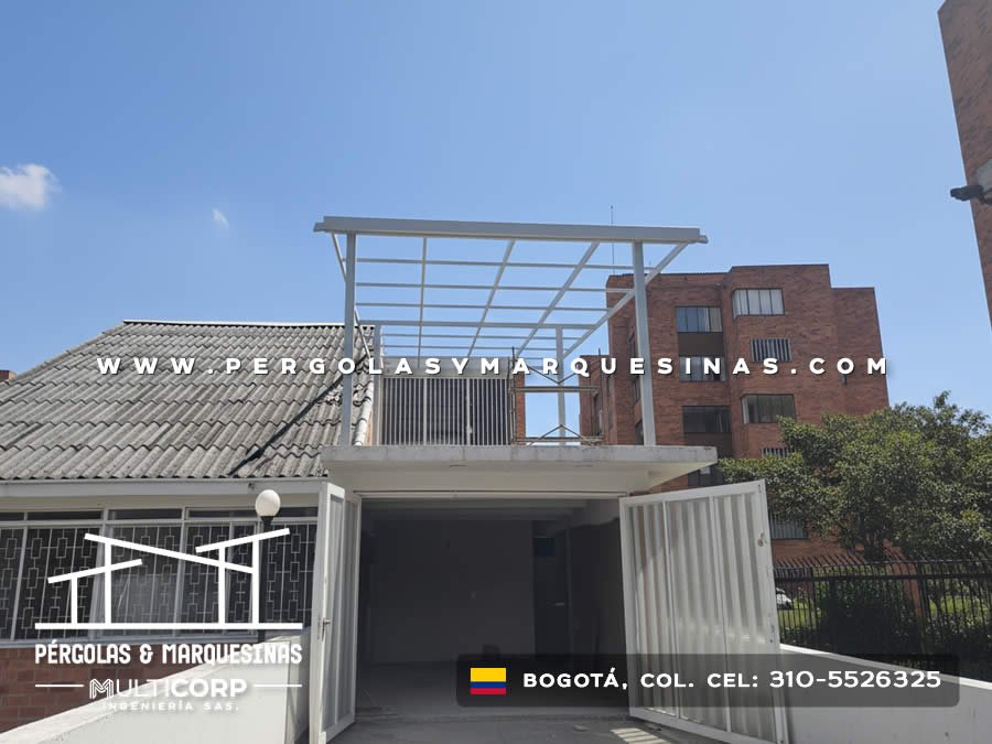 Pergola metalica blanca con retícula abierta sobre porteria de conjunto residencial con edificios en Bogotá, Colombia. Multicorp Ingeniería SAS.
