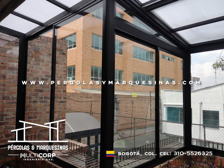 Pergola metalica negra con paneles translucidos sobre patio internal con cancha deportiva y edificios en Bogotá, Colombia. Multicorp Ingeniería SAS.