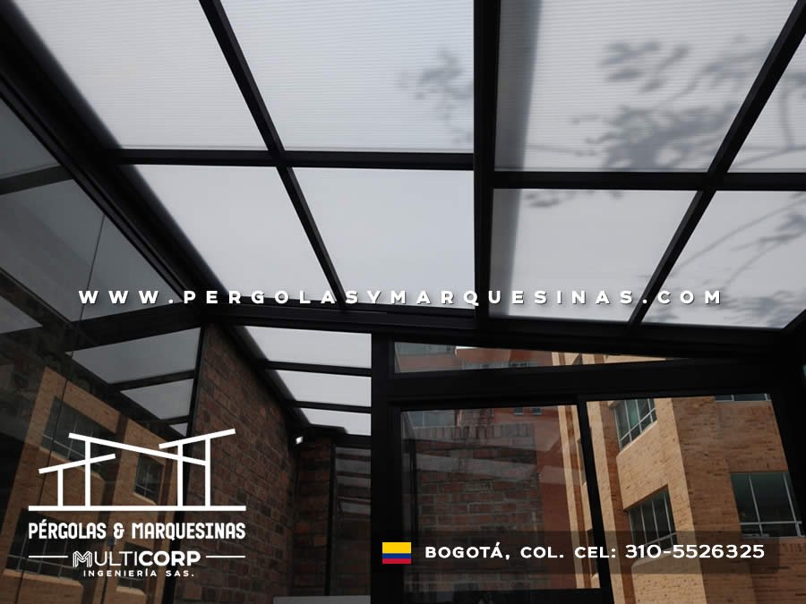 Techo translucido con estructura metalica negra sobre patio interno residencial con vista a edificaciones en Bogotá, Colombia. Multicorp Ingeniería SAS.