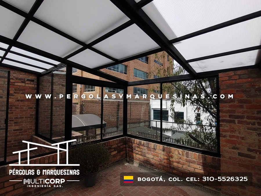 Cubierta de policarbonato con estructura negra y cerramientos de vidrio sobre terraza residencial con piso de baldosa en Bogotá, Colombia. Multicorp Ingeniería SAS.