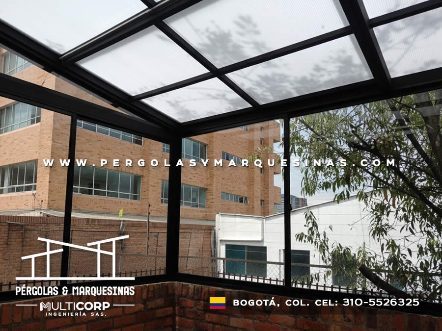 Techo de policarbonato con perfileria negra y ventanas panoramicas sobre terraza residencial con vegetacion urbana en Bogotá, Colombia. Multicorp Ingeniería SAS.