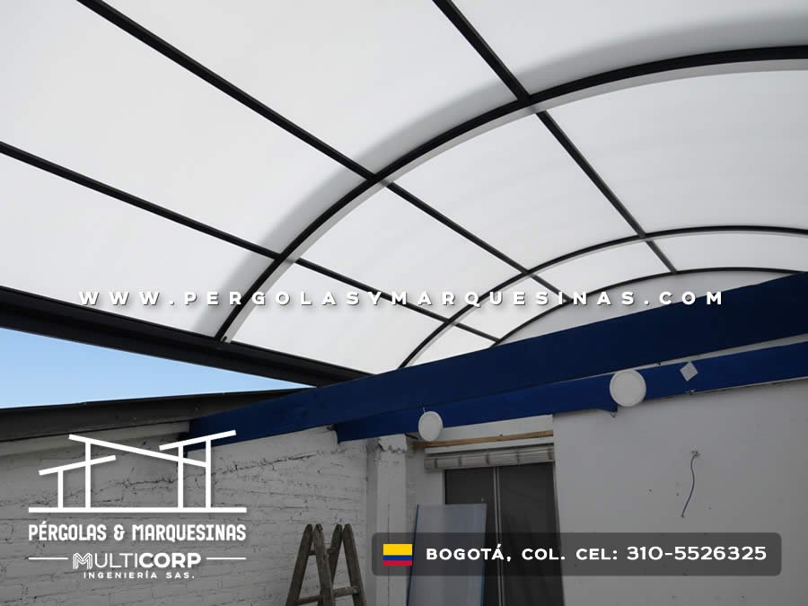 Domo curvo de policarbonato con estructura metalica negra sobre espacio interior con viga azul y muros blancos en Bogotá, Colombia. Multicorp Ingeniería SAS.