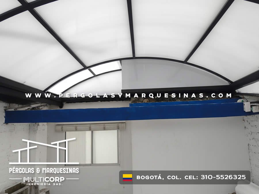 Techo curvo de policarbonato con perfileria negra y columna central sobre espacio interior con ventana corrediza en Bogotá, Colombia. Multicorp Ingeniería SAS.