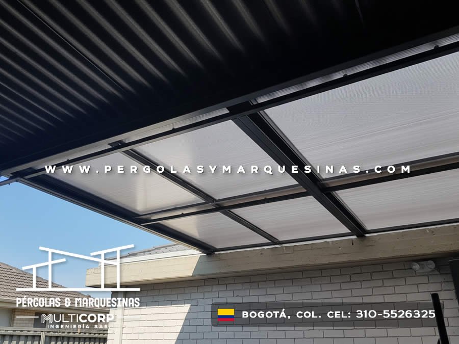 Pergola metalica negra con paneles de policarbonato translucido sobre terraza residencial con muro de ladrillo en Bogotá, Colombia. Multicorp Ingeniería SAS.