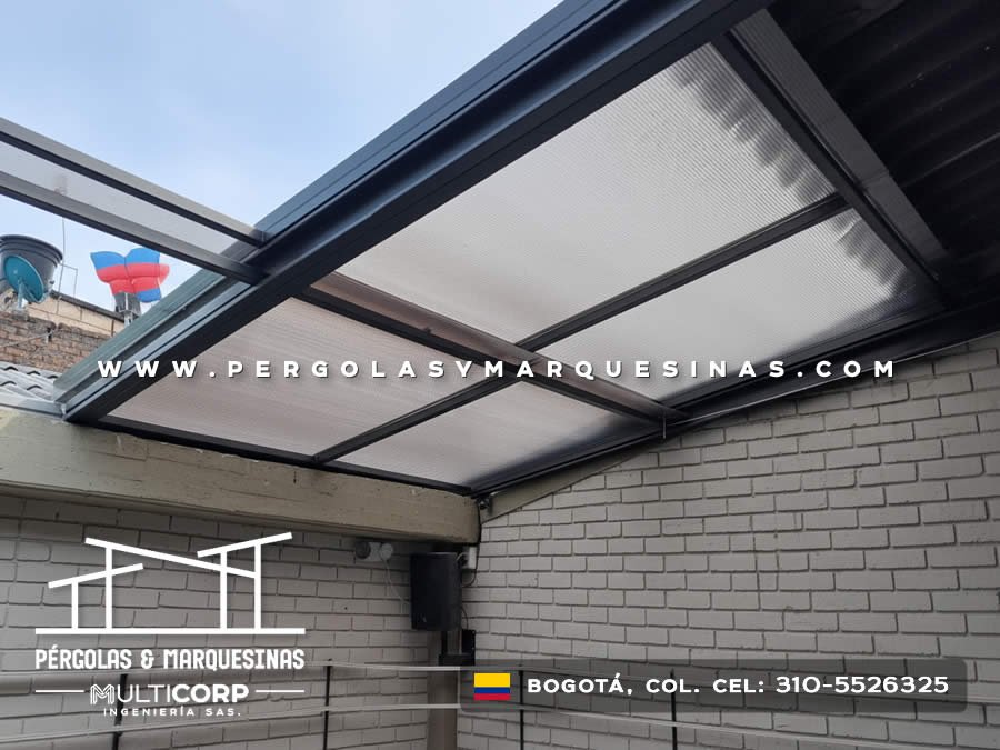 Cubierta de policarbonato con estructura metalica negra sobre terraza lateral de casa con muro gris en Bogotá, Colombia. Multicorp Ingeniería SAS.