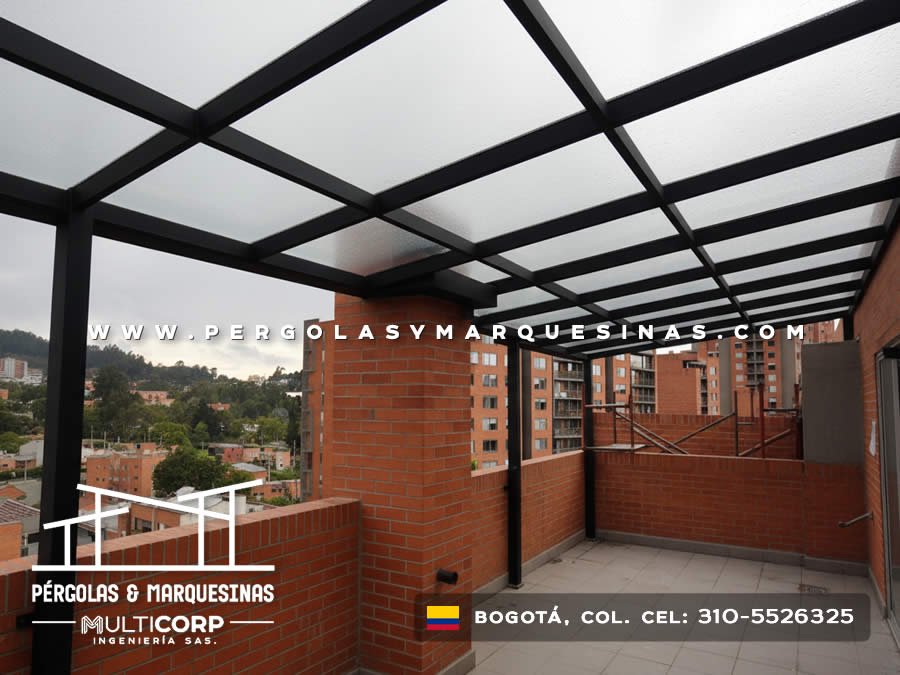 Pergola metalica negra con techo de policarbonato sobre terraza de apartamento con vista urbana y montañas en Bogotá, Colombia. Multicorp Ingeniería SAS.