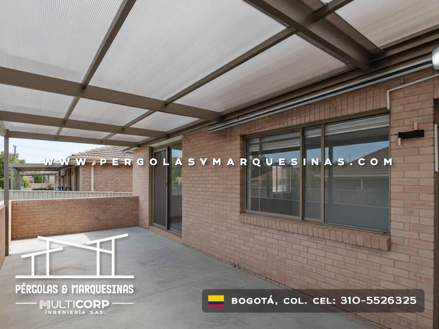 Pergola metalica cafe con cubierta de policarbonato sobre terraza de casa con puerta de vidrio y muro de ladrillo en Bogotá, Colombia. Multicorp Ingeniería SAS.