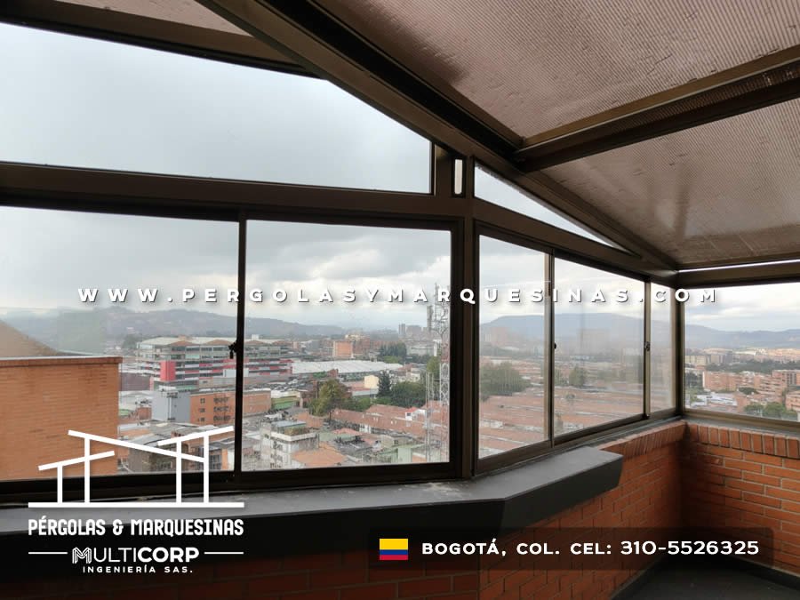 Pergola cerrada acristalada con estructura de aluminio oscuro en balcon de apartamento con vista a montanas en Bogotá, Colombia. Multicorp Ingeniería SAS.