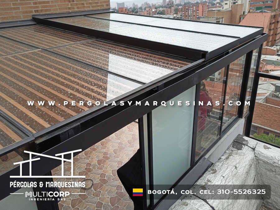 Cubierta de policarbonato con estructura metalica negra y vidrio en terraza de atico con piso de piedra en Bogotá, Colombia. Multicorp Ingeniería SAS.