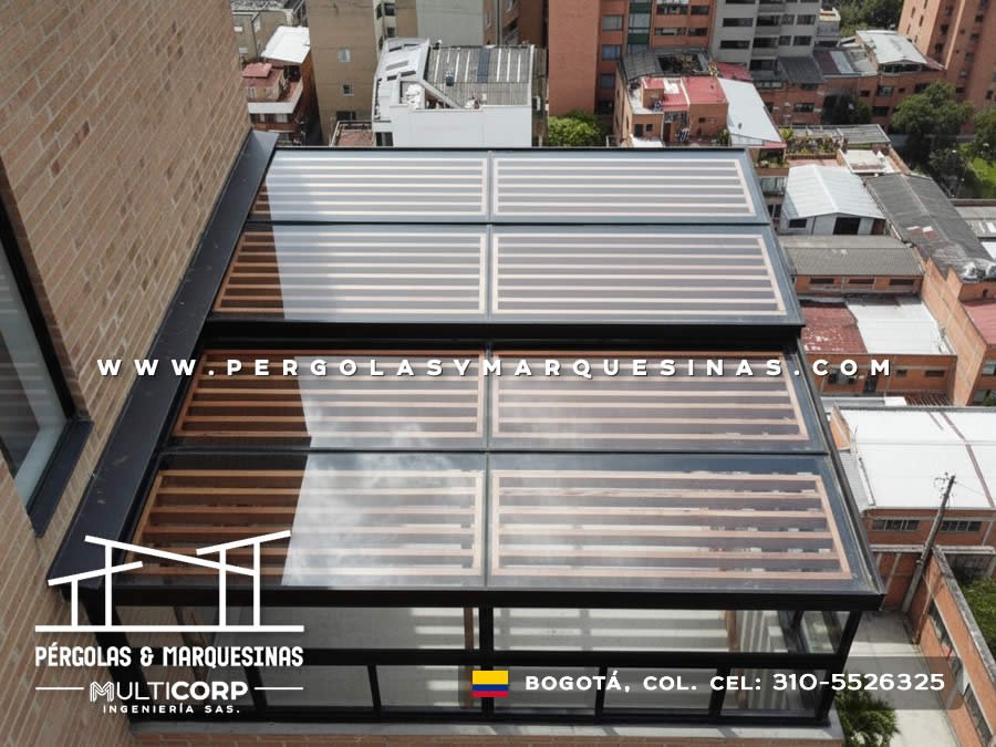 Techo de policarbonato con estructura metalica negra y lamas de madera en terraza de atico con vista a la ciudad en Bogotá, Colombia. Multicorp Ingeniería SAS.