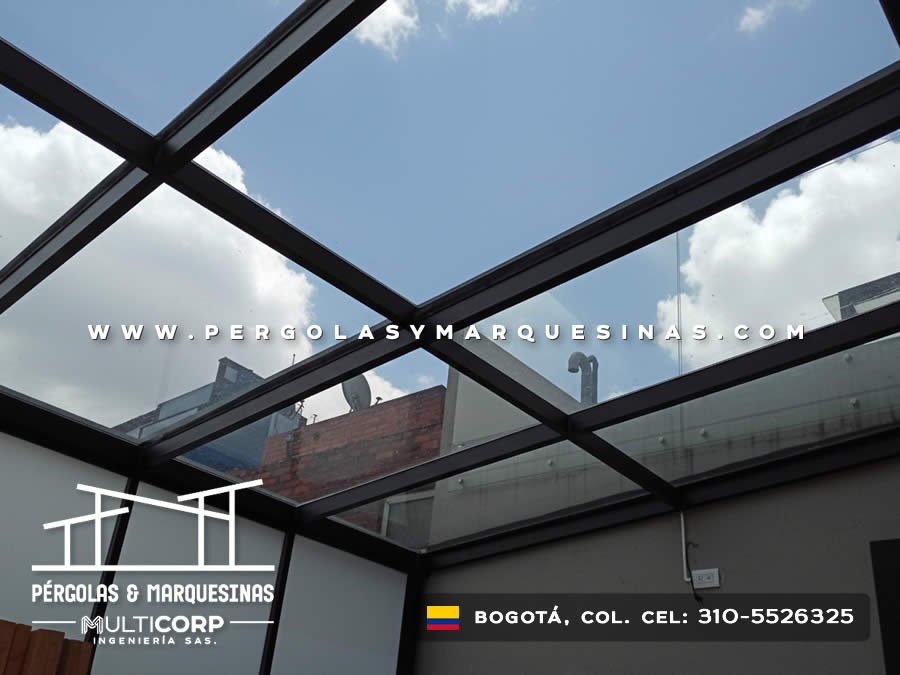 Pergola con techo de vidrio templado estructura metalica negra y muro en terraza de atico urbano en Bogotá, Colombia. Multicorp Ingeniería SAS.