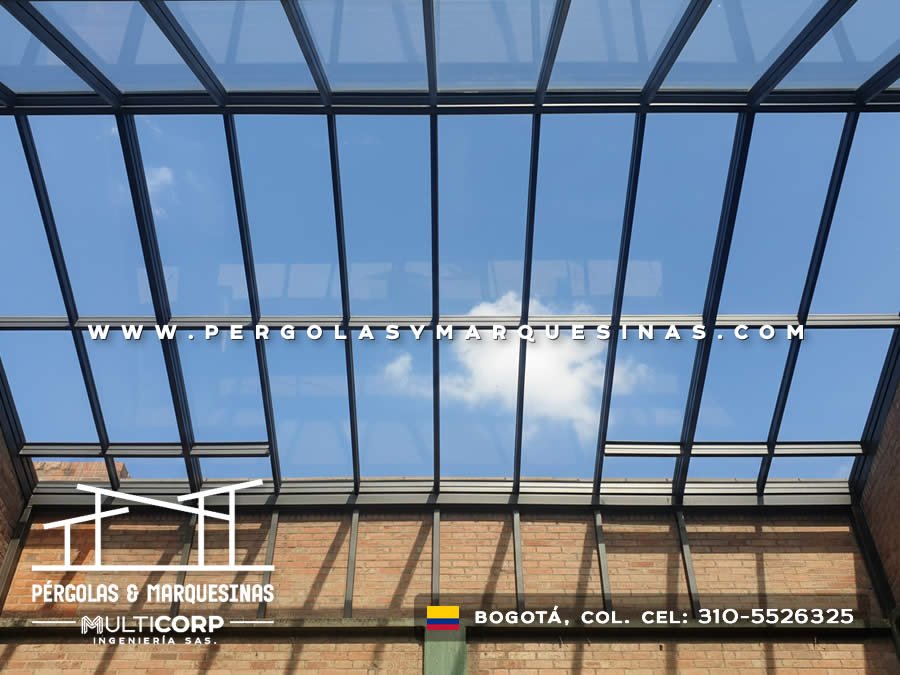 Cubierta de vidrio templado con estructura metalica oscura en terraza con muro de ladrillo y vista al cielo en Bogotá, Colombia. Multicorp Ingeniería SAS.