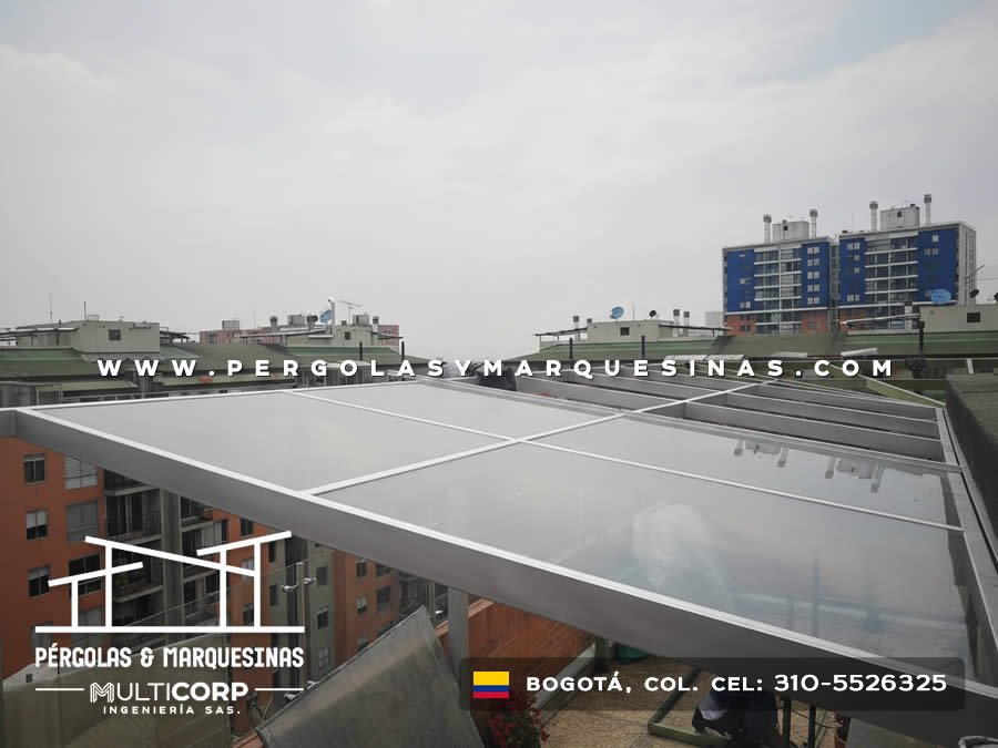 Cubierta de policarbonato con estructura metalica gris en terraza de edificio con vista a edificaciones urbanas en Bogotá, Colombia. Multicorp Ingeniería SAS.