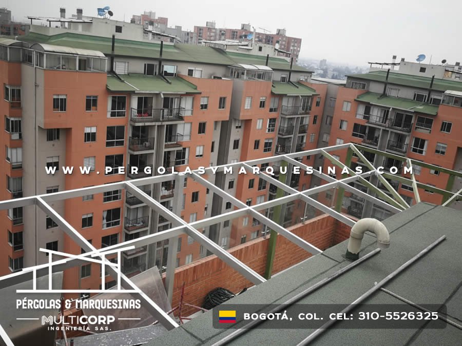 Estructura metalica gris para cubierta de vidrio en terraza de edificio con vista a edificaciones urbanas en Bogotá, Colombia. Multicorp Ingeniería SAS.