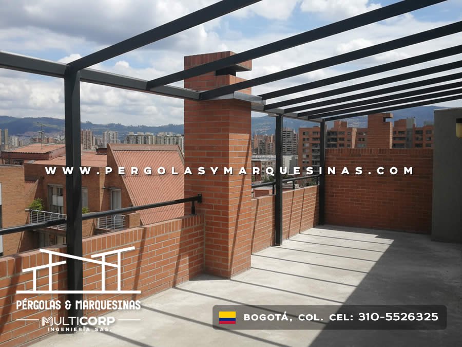 Pergola con estructura metalica negra en azotea de edificio con chimenea de ladrillo y vista a edificaciones urbanas en Bogotá, Colombia. Multicorp Ingeniería SAS.
