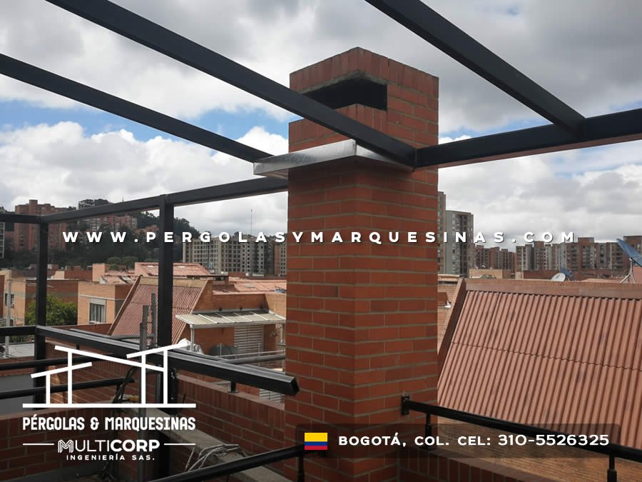 Pergola con estructura metalica negra en azotea con chimenea de ladrillo y vista a edificios urbanos en Bogotá, Colombia. Multicorp Ingeniería SAS.