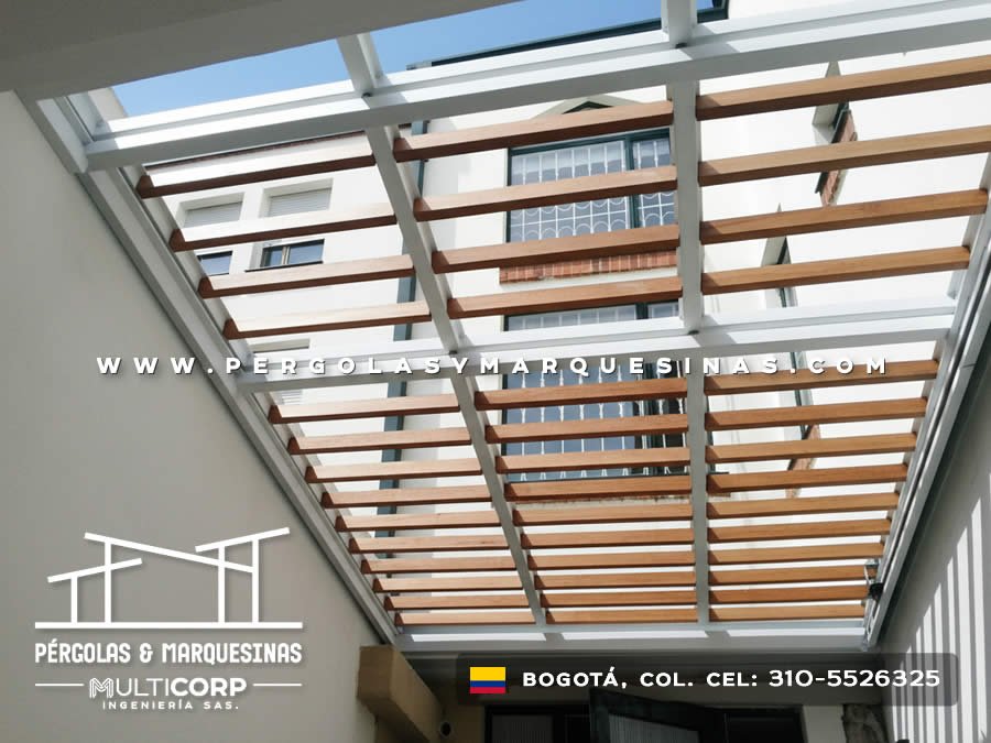 Pergola con listones de madera y estructura metalica blanca en zona exterior entre edificaciones urbanas en Bogotá, Colombia. Multicorp Ingeniería SAS.
