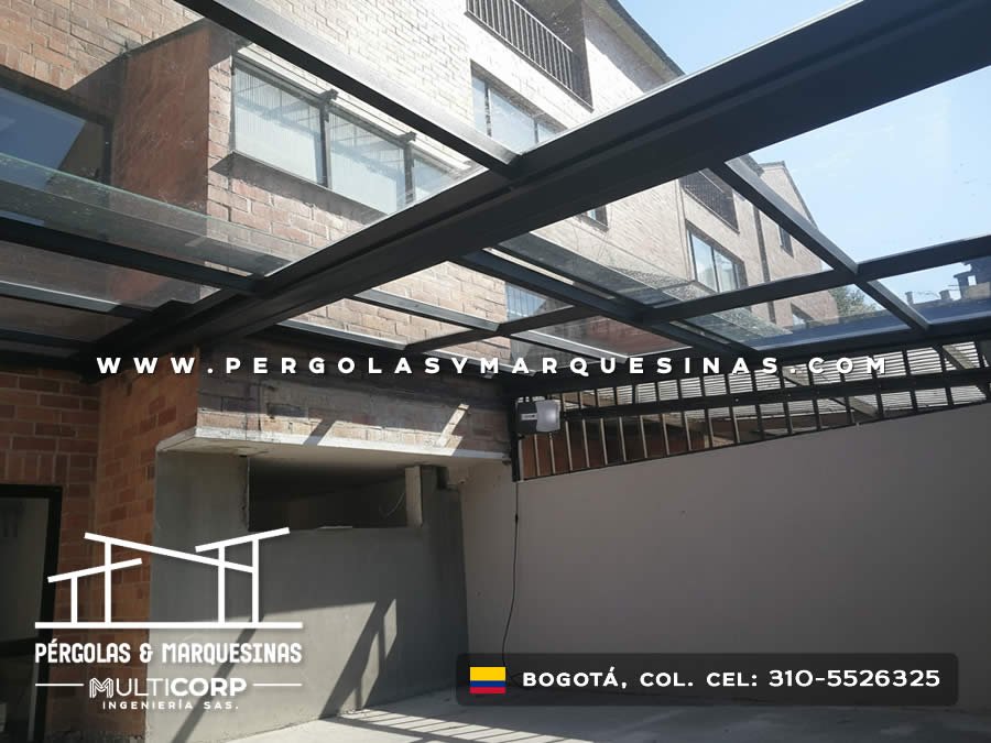 Techo de vidrio con estructura metalica oscura en patio entre edificios de ladrillo en Bogotá, Colombia. Multicorp Ingeniería SAS.