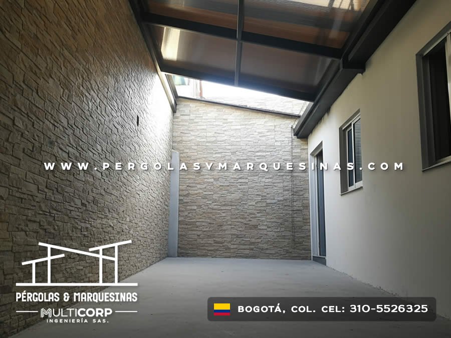 Techo de policarbonato con estructura metalica oscura en patio con muros de piedra natural en Bogotá, Colombia. Multicorp Ingeniería SAS.