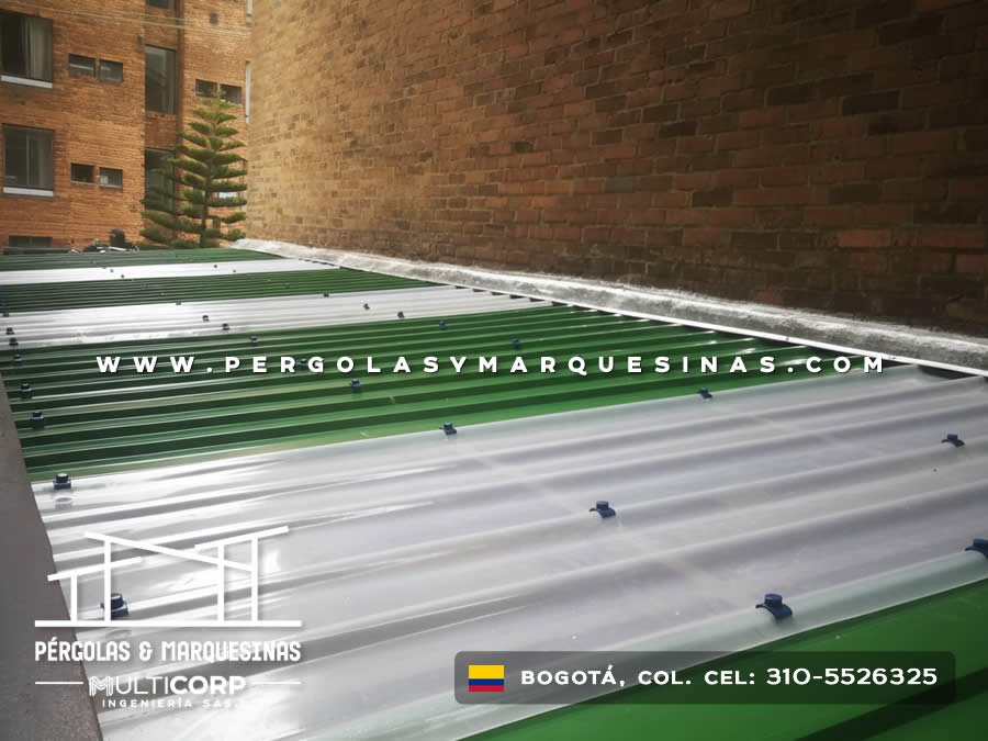 Paneles de policarbonato verde con perfiles de aluminio en azotea junto a edificio de ladrillo en Bogotá, Colombia. Multicorp Ingeniería SAS.