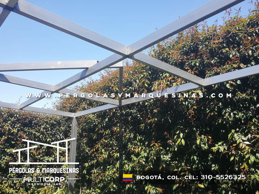 Pergola con estructura galvanizada abierta en jardin con vegetacion frondosa y cielo azul en Bogotá, Colombia. Multicorp Ingeniería SAS.