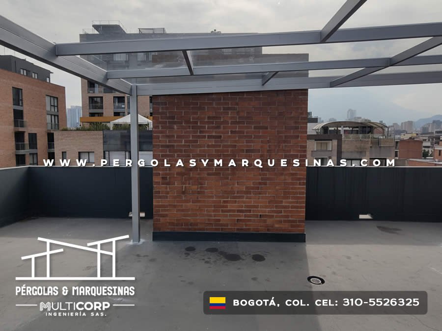 Pergola con estructura gris en azotea moderna con modulo de ladrillo y vista al skyline urbano en Bogotá, Colombia. Multicorp Ingeniería SAS.