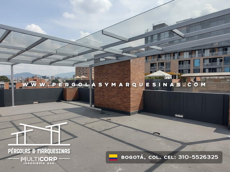 Cubierta de vidrio con estructura gris en azotea con modulo de ladrillo y edificios modernos al fondo en Bogotá, Colombia. Multicorp Ingeniería SAS.