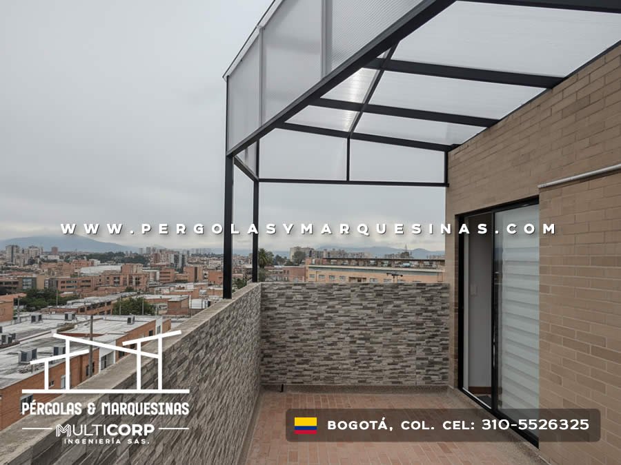 Pergola con estructura oscura y policarbonato en terraza con muro de piedra y vista panoramica urbana en Bogotá, Colombia. Multicorp Ingeniería SAS.