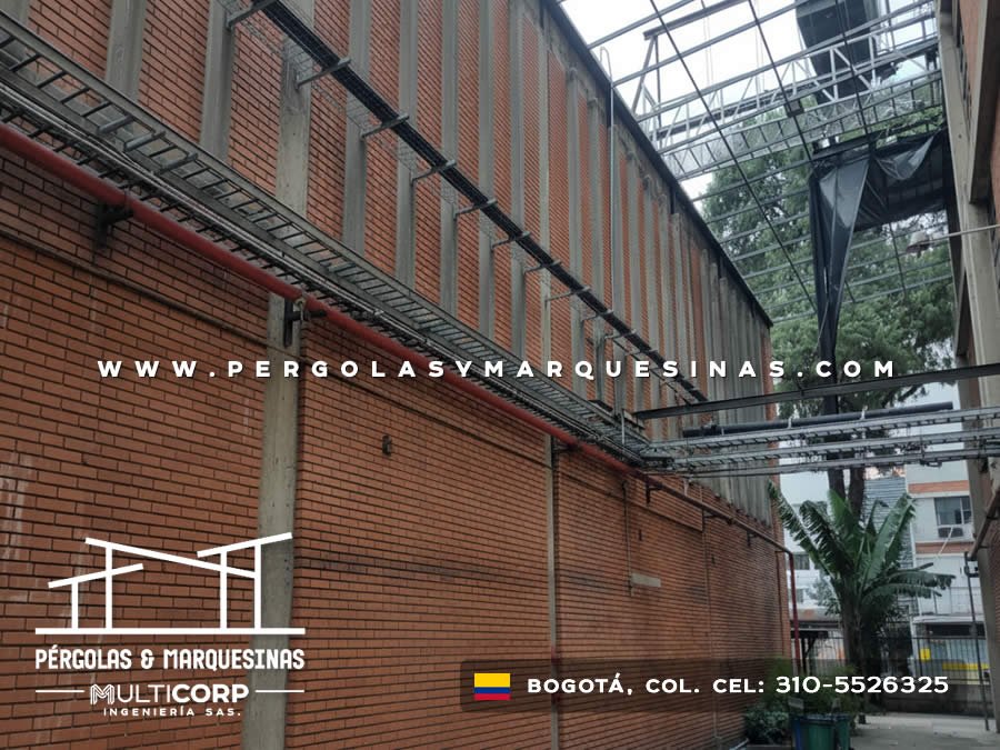 Estructura metalica en pasillo entre edificios de ladrillo con cables y vegetacion en Bogotá, Colombia. Multicorp Ingeniería SAS.