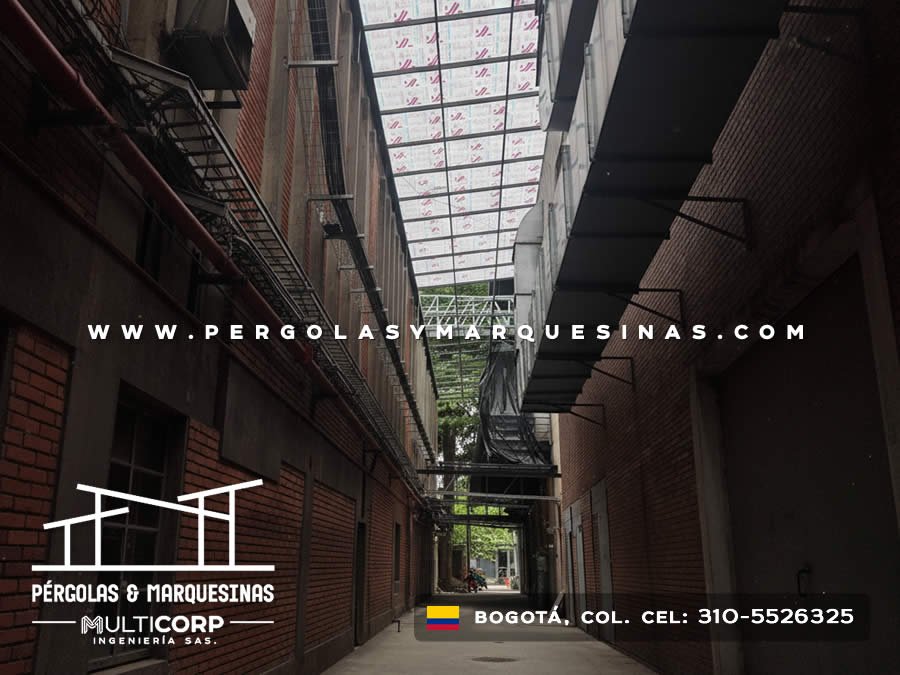 Techo translucido con estructura metalica oscura pasillo estrecho muros ladrillo edificio en Bogotá, Colombia. Multicorp Ingeniería SAS.