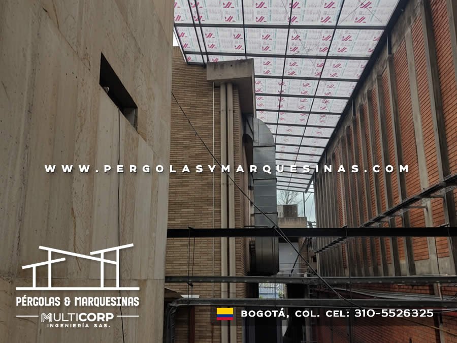 Techo translucido con grilla metalica oscura pasillo tres pisos muros ladrillo concreto aparente en Bogotá, Colombia. Multicorp Ingeniería SAS.
