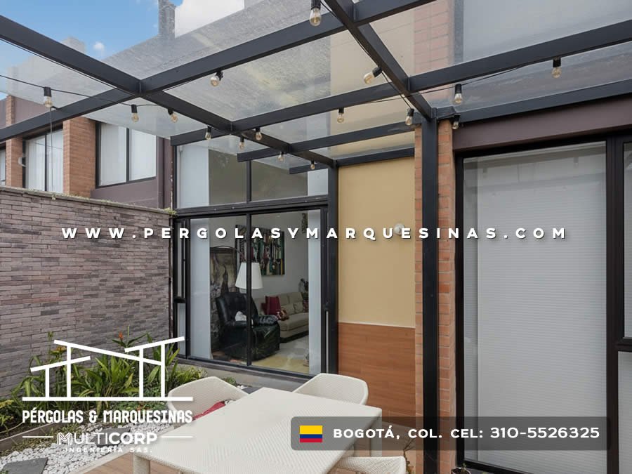 Pergola metalica negra vidrio templado iluminacion terraza residencial muro piedra cesped jardin en Bogotá, Colombia. Multicorp Ingeniería SAS.