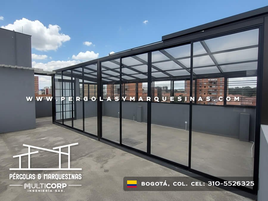 Pergola metalica negra vidrio templado terraza cerrada divisiones interiores edificios urbanos cielo azul en Bogotá, Colombia. Multicorp Ingeniería SAS.