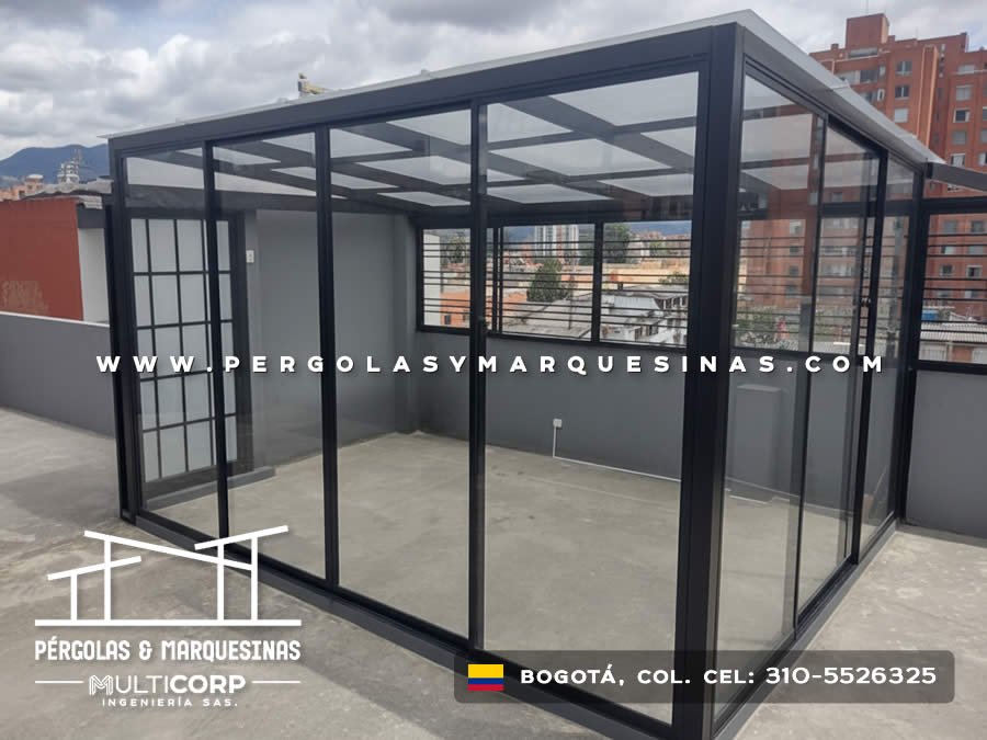 Cubierta metalica negra vidrio templado terraza cerrada divisiones rejilla edificios urbanos cielo nublado en Bogotá, Colombia. Multicorp Ingeniería SAS.