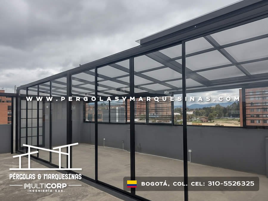 Cubierta metalica negra vidrio templado terraza cerrada divisiones interiores edificios urbanos cielo nublado en Bogotá, Colombia. Multicorp Ingeniería SAS.