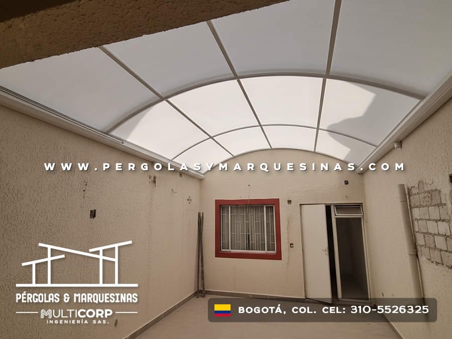 Cubierta curva policarbonato estructura metalica patio interior ventana roja puerta muros blancos en Bogotá, Colombia. Multicorp Ingeniería SAS.