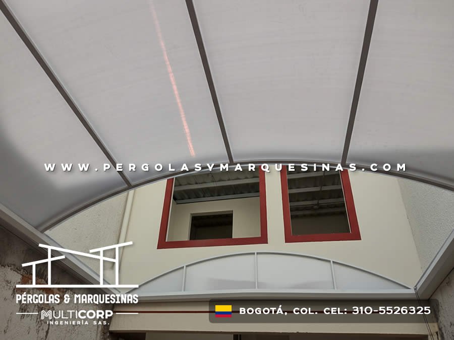 Cubierta curva policarbonato estructura metalica patio interior ventanas rojas muros blancos construccion en Bogotá, Colombia. Multicorp Ingeniería SAS.
