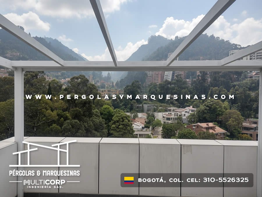 Pérgola metálica blanca vigas cruzadas terraza baranda vidrio vista urbana montañosa en Bogotá, Colombia. Multicorp Ingeniería SAS.