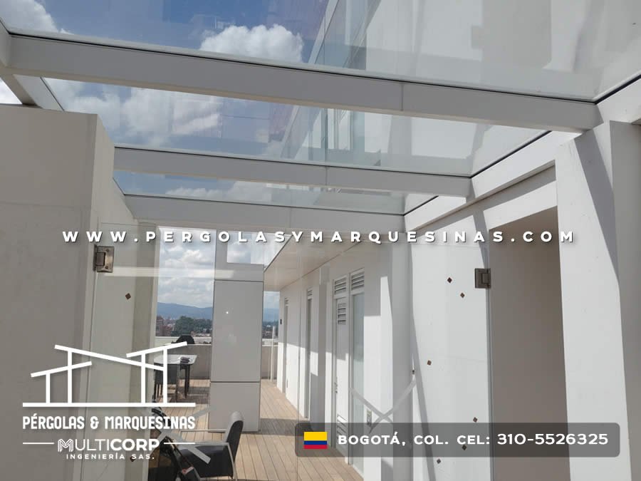 Cubierta vidrio templado estructura metálica blanca terraza muros blancos mobiliario exterior en Bogotá, Colombia. Multicorp Ingeniería SAS.