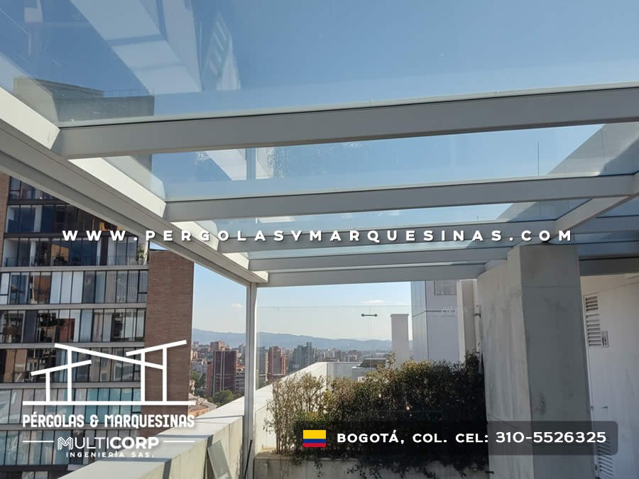 Pérgola vidrio templado estructura metálica gris terraza vista panorámica muros blancos jardinera en Bogotá, Colombia. Multicorp Ingeniería SAS.