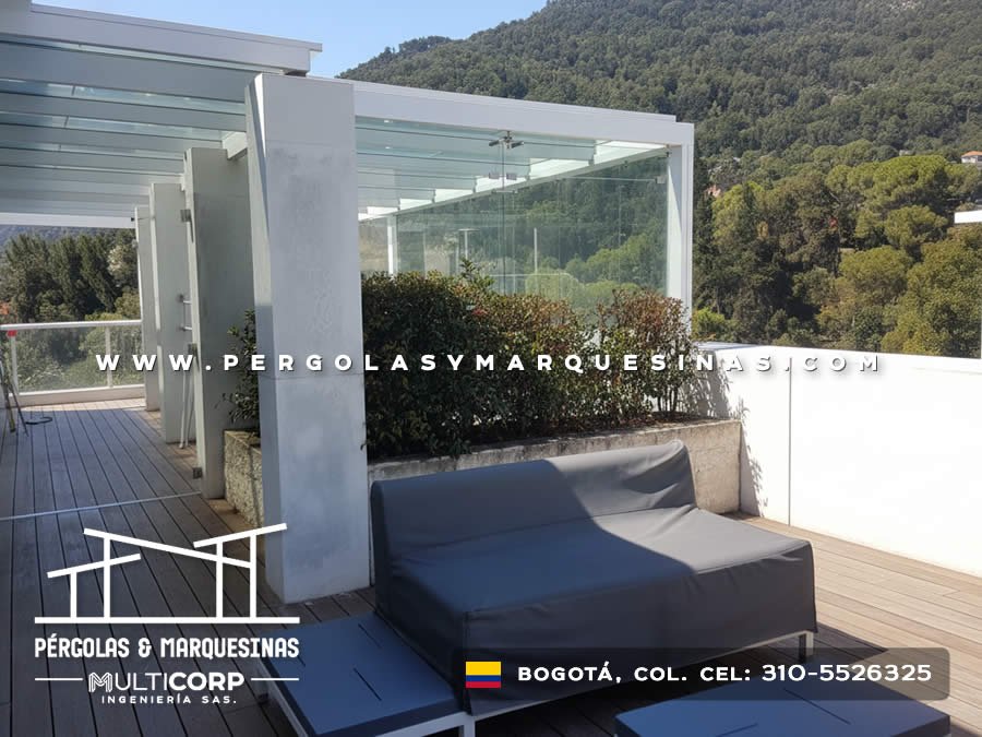 Pérgola vidrio templado estructura blanca terraza piso madera jardinera arbustos mobiliario exterior en Bogotá, Colombia. Multicorp Ingeniería SAS.