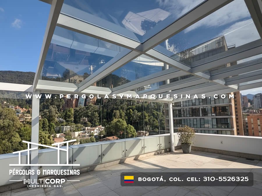 Pergola con vidrio templado y barandilla de vidrio en terraza de edificio con vista a montes y ciudad en Bogotá, Colombia. Multicorp Ingeniería SAS.