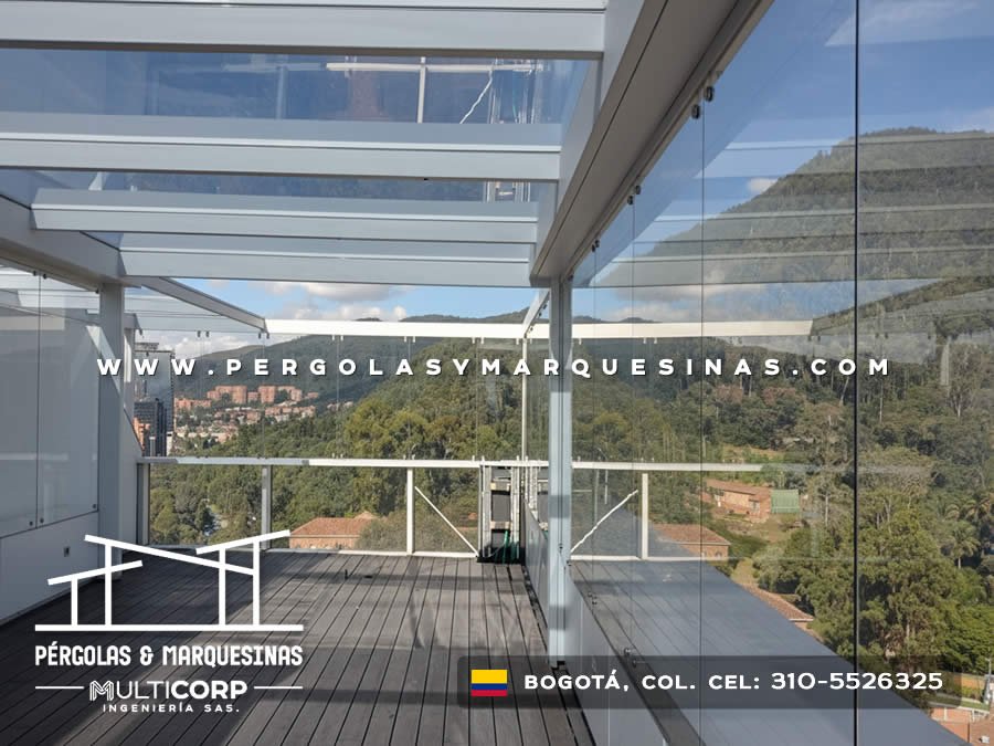 Pergola con vidrio templado y cerramiento lateral de vidrio en terraza con deck de madera y vista a montes en Bogotá, Colombia. Multicorp Ingeniería SAS.