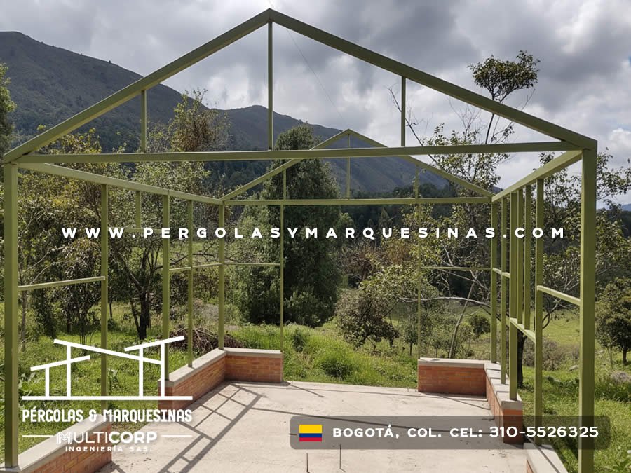 Pergola metalica verde con estructura de techo triangular y base de ladrillo en zona rural con montanas en Bogotá, Colombia. Multicorp Ingeniería SAS.