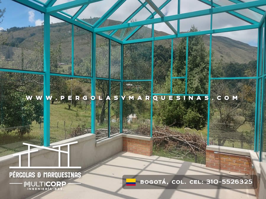 Pergola con estructura turquesa y paneles de vidrio en zona rural con vista a montanas cercana a Bogotá, Colombia. Multicorp Ingeniería SAS.